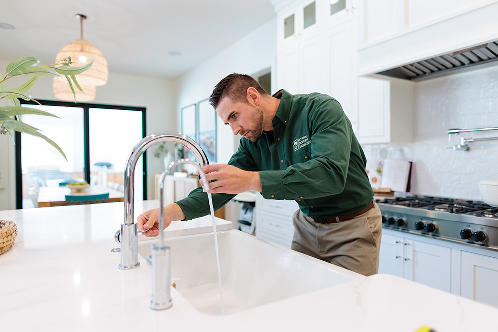 An NPI inspector turns on a kitchen sink and examines the faucet.