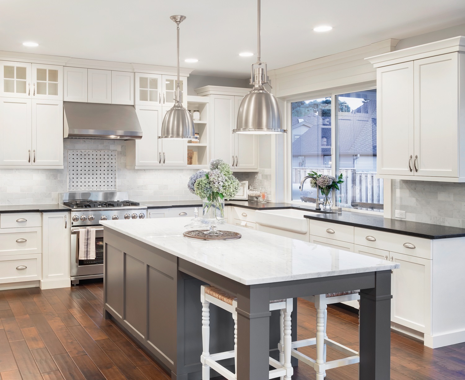 A well-lit luxury kitchen with white and black countertops and a large kitchen island.