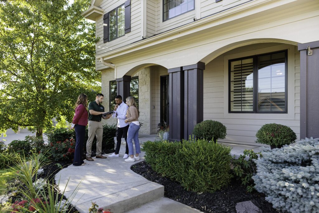 An NPI inspector discusses his findings with clients in front of a beautiful home.