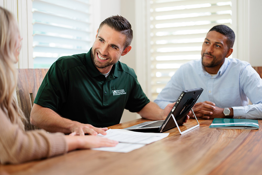 An NPI inspector discusses his report with two happy clients.
