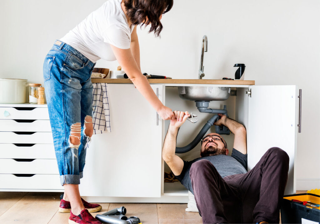Man fixes plumbing under the sink.